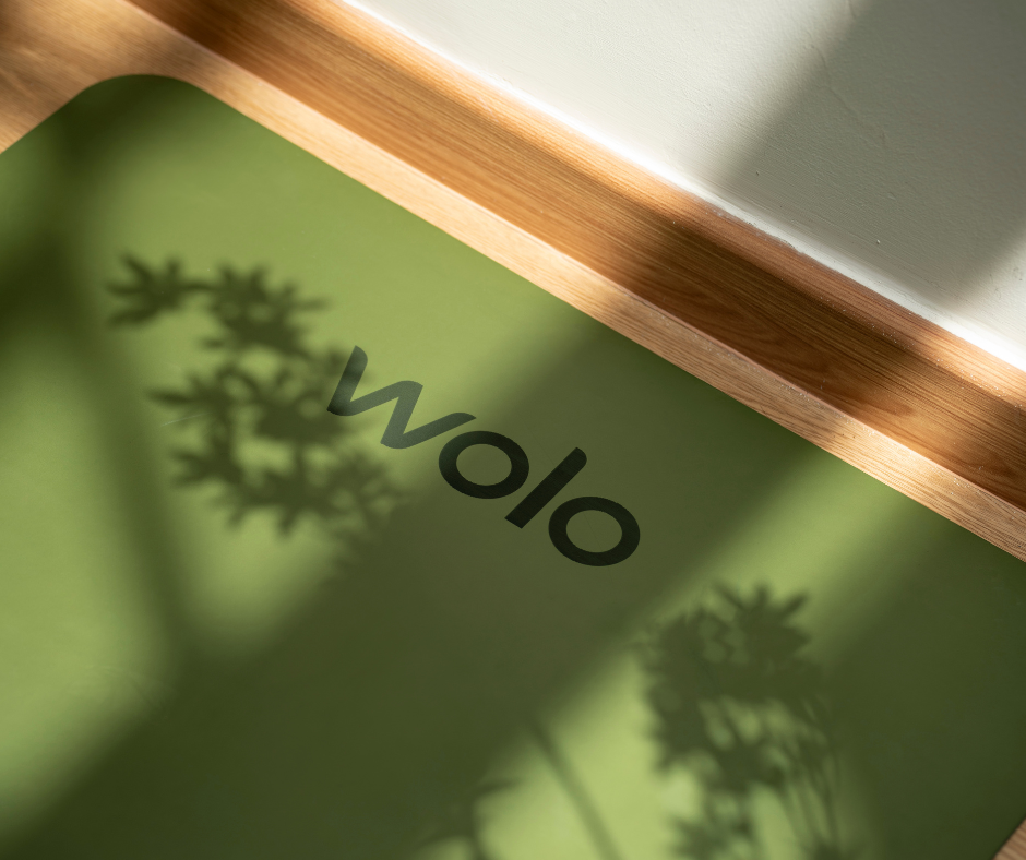 Green mat with 'wolo' branding and shadow of plants on a wooden surface.