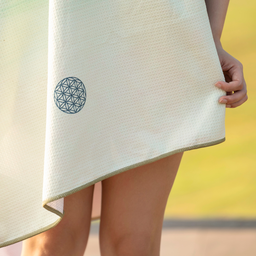 person holding a yoga towel with a flower of life design#color_verdant flow