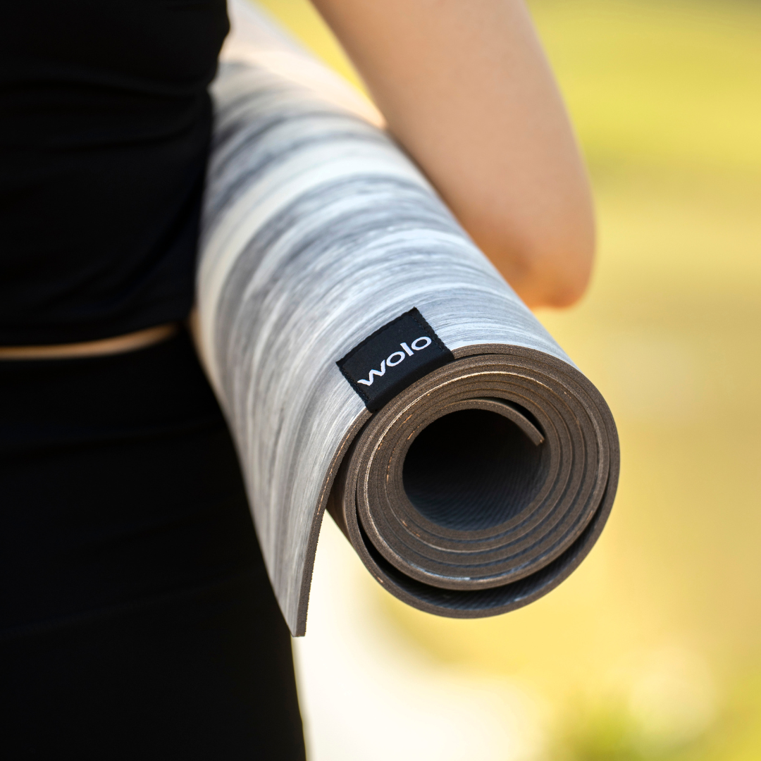 Rolled-up yoga mat with 'wolo' branding held by a person#color_limestone grey