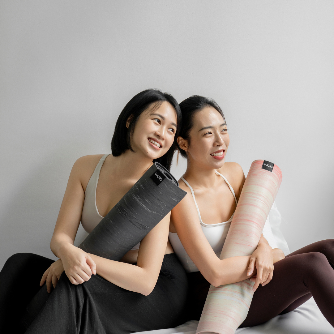 Two women holding Wolo Ascend yoga mats