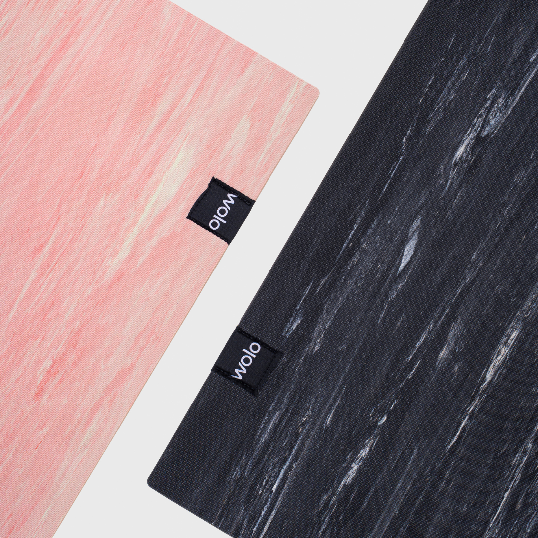 Two textured yoga mats, one pink and one black, with Wolo brand labels on a white background.