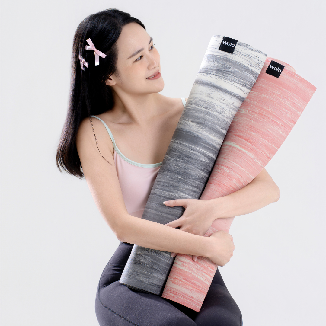 Woman holding a pink and gray yoga mat with a white background