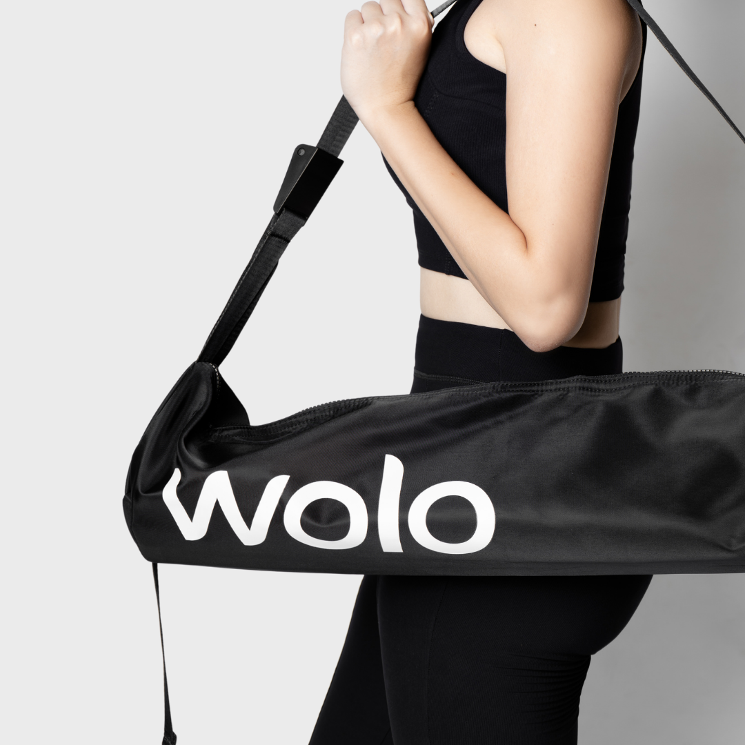 Person holding a black Wolo bag against a gray background