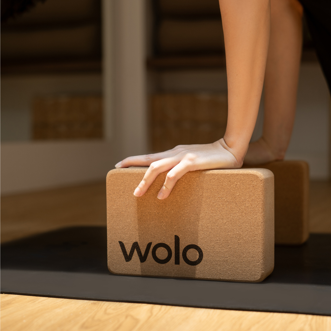 Person using a yoga block with 'wolo' branding on a mat.