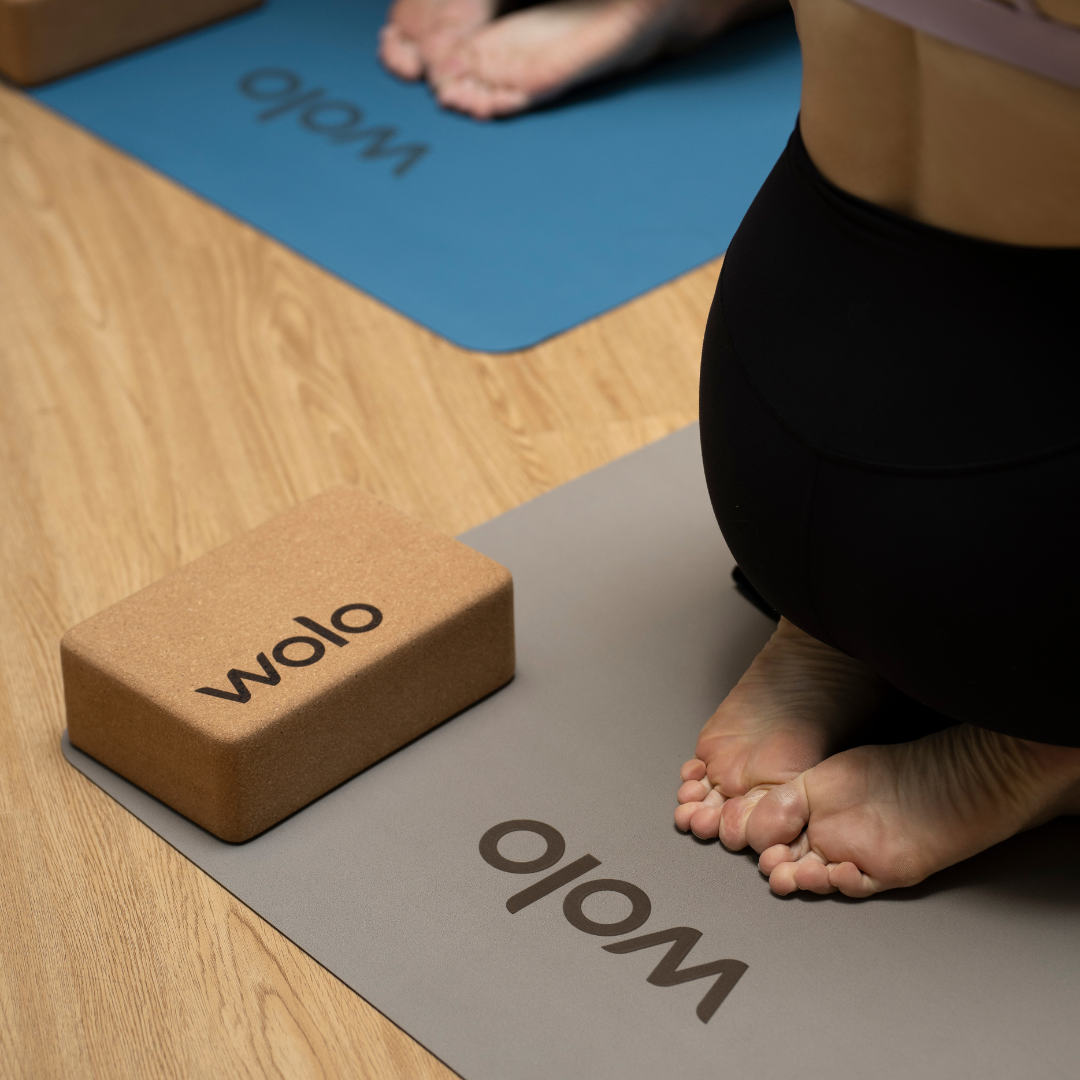 Yoga mat and block on a wooden floor with 'wolo' branding.