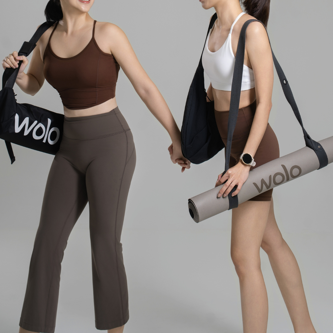 Two women holding Wolo bags and a yoga mat on a gray background