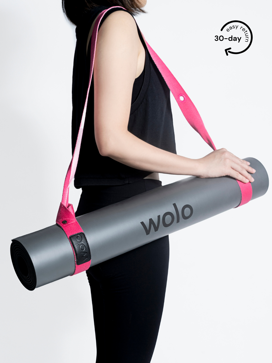 Lady carry a grey yoga mat with a pink mat carry strap