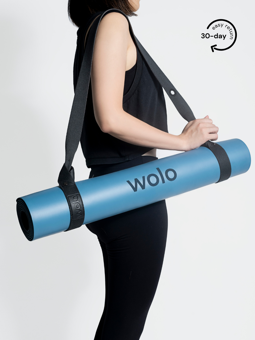 Lady carry a blue yoga mat with a grey yoga mat carry strap
