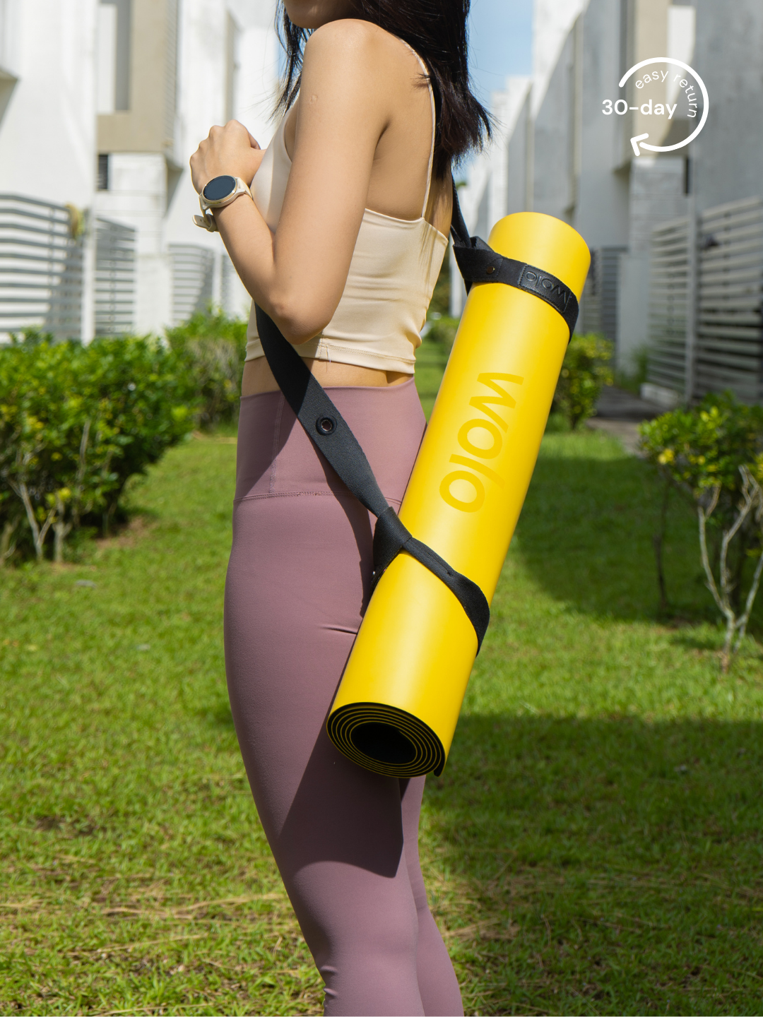 Lady carry a yellow yoga mat with a grey yoga mat carry strap