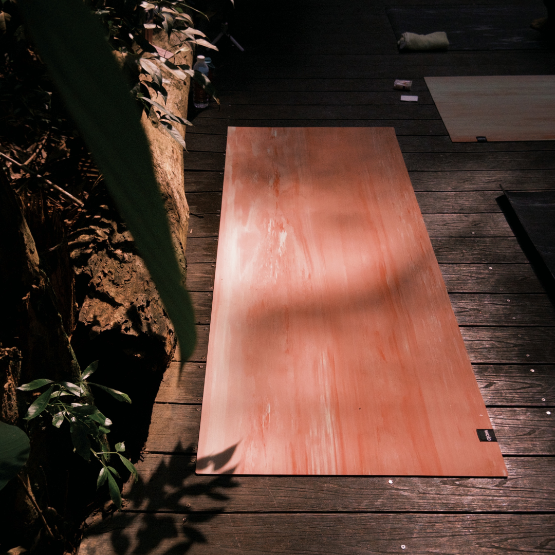 Dark wooden deck with plant and Wolo Ascend Yoga Mat.#color_unakite pink