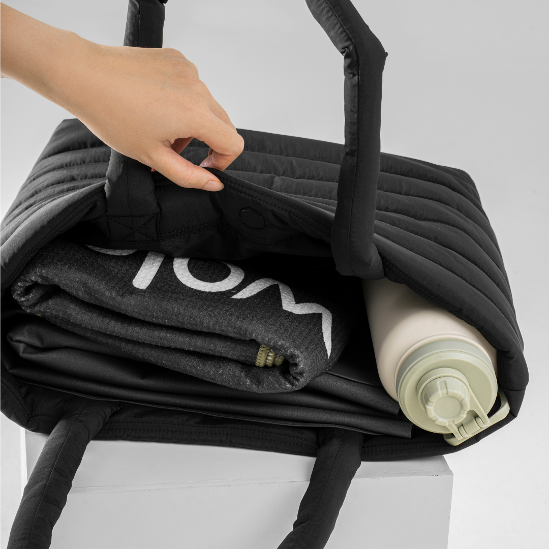 Black bag with a rolled-up towel and a bottle inside#color_onyx black