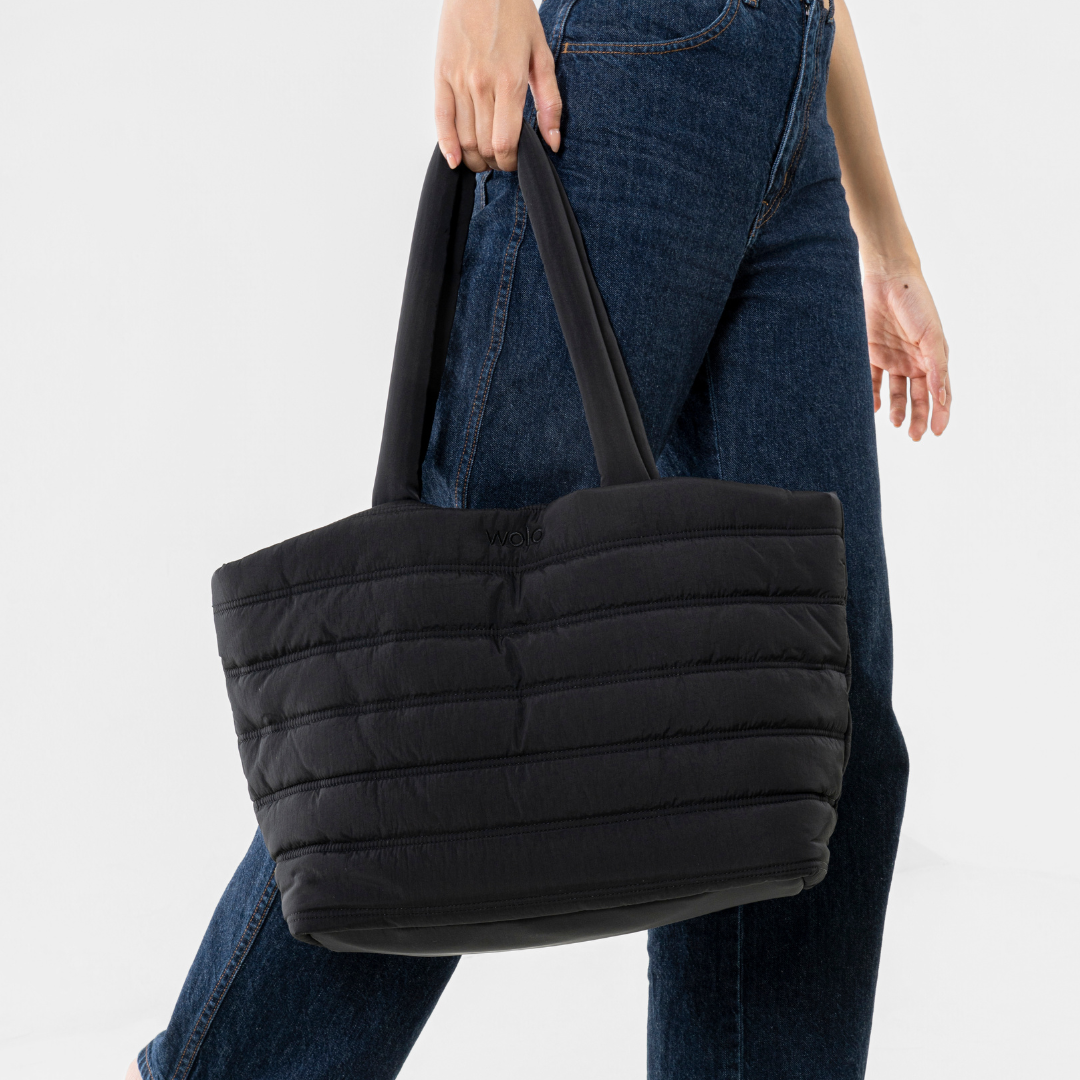 Person holding a black quilted tote bag#color_onyx black