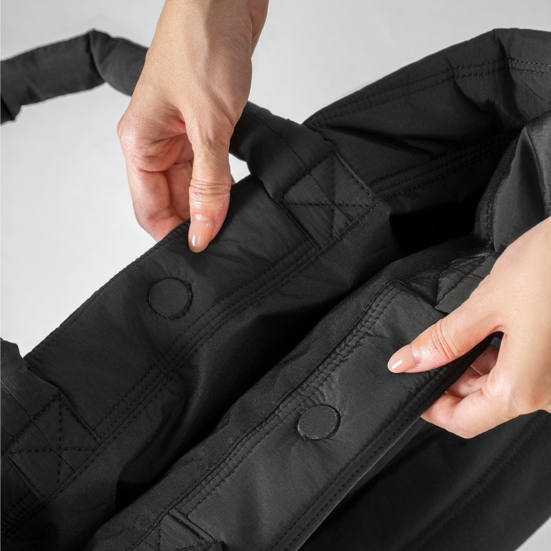Close-up of a person adjusting a black quilted tote#color_onyx black