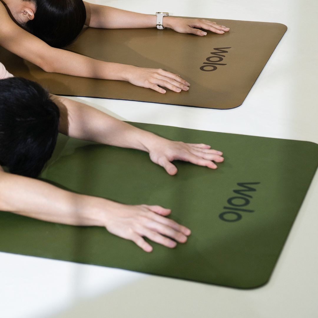 Two people stretching on Wolo yoga mats, one khaki and one green