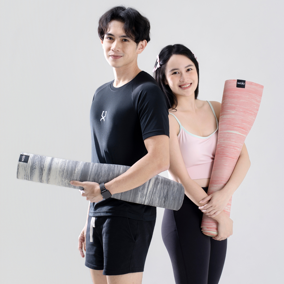 Two people holding yoga mats on a plain background