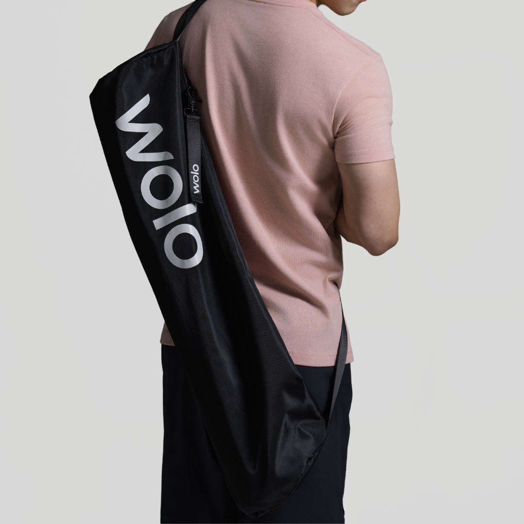 Person holding a black drawstring bag with 'WOIO' branding on a light gray background