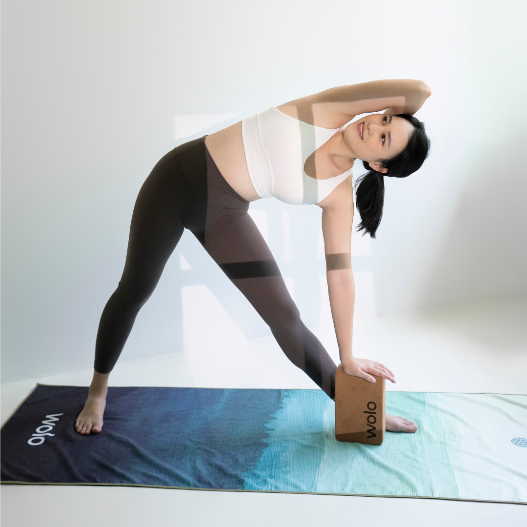 Woman practicing yoga with a Wolo brand mat and block on a white background